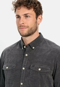 Gray corduroy shirt with a button-down collar, featuring two chest pockets, beige buttons, and a subtle textured pattern.