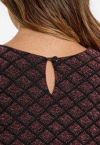 Black fabric with a maroon diamond pattern, featuring a keyhole back and a black button closure. Smooth texture and fitted design.