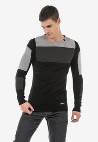 Schwarzer und grauer langärmeliger Pullover mit horizontalen Rippmustern, runder Ausschnitt und strukturierten Akzenten an den Ärmeln. Verfügt über ein kleines Logo-Label.