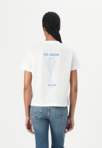 White cotton t-shirt with short sleeves, featuring a blue graphic of an ice cream cone and text "ICE CREAM PLEASE" on the back.