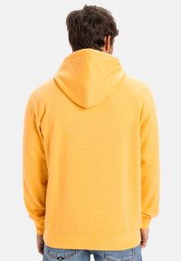 Yellow hoodie with a drawstring hood, long sleeves, and ribbed cuffs. Made of soft fabric, features a smooth texture with no visible patterns.