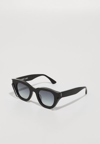 Gafas de sol negras con montura en forma de ojo de gato, angular y de gran tamaño, lentes graduales en gris y acabado brillante suave. Logo minimalista en la patilla.