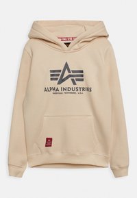 Felpa beige con logo Alpha Industries e testo "Knoxville, Tennessee, U.S.A.", tasca frontale e etichetta rossa vicino all'orlo.