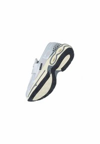 Grijze sport schoen met een mesh bovenwerk, een gevoerde band en een dikke zool met een gestructureerde zwarte onderkant en cirkelvormige looppatronen.