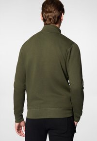 Olive zielony polarowy sweter z kołnierzem typu stand-up, ściągaczami na rękawach i hemie. Charakteryzuje się gładką fakturą i minimalistycznym designem.