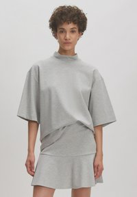 Grijze oversized top met korte mouwen, een opstaande kraag, gelaagd ontwerp en een uitlopende zoom. Soepele textuur en casual silhouet.