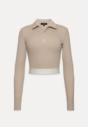 Polo stylová zkrácená halenka z světle béžového žebrovaného materiálu, s límečkem, trojitou knoflíkovou légou a bílým pásem s logem "LA MANIA" na lemu.