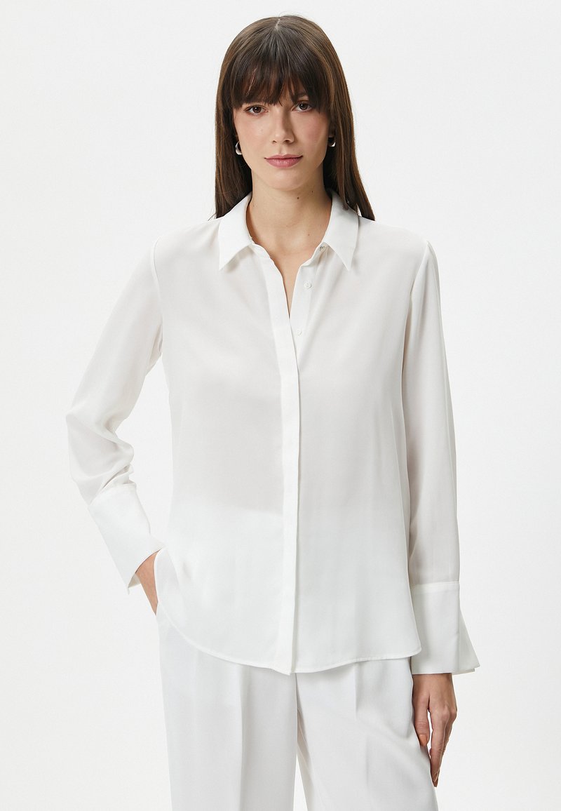 Witte zijden blouse met een knoopsluiting aan de voorkant, lange mouwen en een ontspannen pasvorm. Kenmerkt een klassieke kraag en een licht afgeronde zoom.