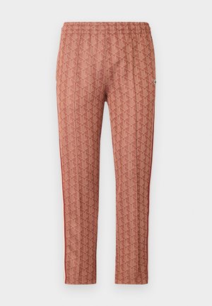 Pantalon rouge à motifs avec un design géométrique, taille élastique et rayures sur les côtés. Fabriqué avec un tissu à texture lisse.