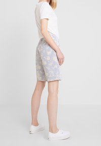 Lichtblauwe shorts met een bloemmotief in pastelkleuren. Gemaakt van zachte stof, met een ontspannen pasvorm en een tailleband met riemlussen.