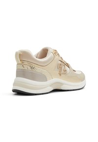 Zapatilla beige con parte superior de cuero suave, acentos texturizados y un collar acolchado. Presenta una entresuela acolchada y suela de goma negra.
