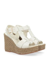 Sandales compensées blanches avec plateforme en jute tressé, bout ouvert et design à large bride. Caractéristiques d'une fermeture à boucle et d'une texture en cuir lisse.