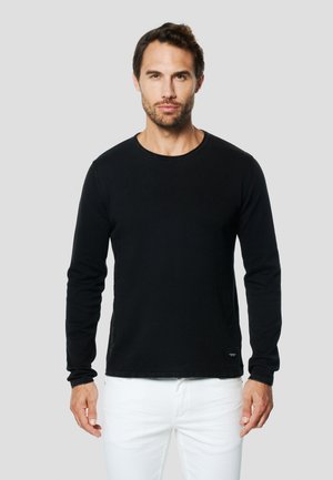 Camiseta negra de manga larga con escote redondo y diseño ajustado. La tela parece suave; presenta una textura sutil y un pequeño logo en el dobladillo.