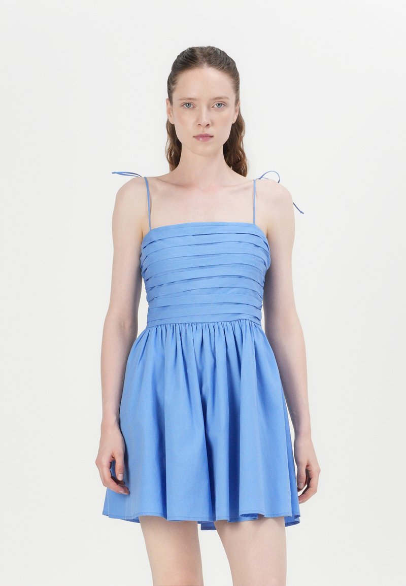 Light blue dress with a fitted bodice featuring horizontal pleats, thin adjustable straps, and a flared skirt. Smooth cotton fabric.