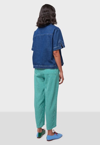Camicia di denim con una vestibilità rilassata, maniche corte, pantaloni blu a strisce e scarpe colorate con accenti blu, verdi e rossi.