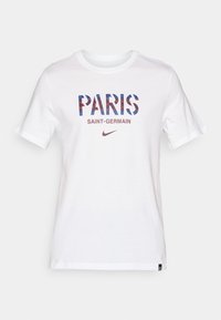 Balta trumpa rankovėmis marškinėliai su užrašu "PARIS" mėlynomis ir raudonomis geometrinėmis raidėmis ir "SAINT-GERMAIN" mažesniu tekstu po juo. Įtrauktas Nike logotipas.