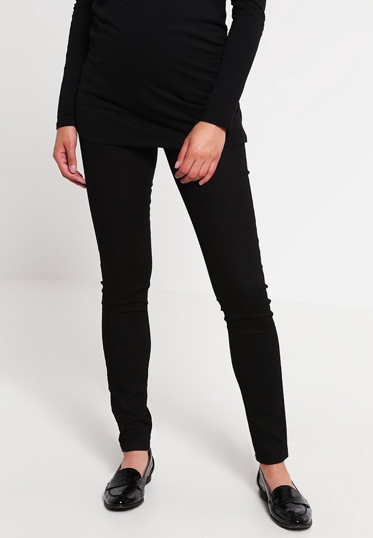 Leggings noirs extensibles avec un design ajusté, associés à des mocassins noirs en cuir verni. Le haut est une chemise noire à manches longues, couvrant les hanches.