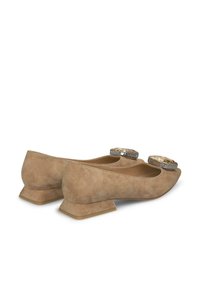 Ballerine in suede beige con un leggero tacco, dotate di grandi gemme decorative sulla punta e una fodera interna liscia. Design a punta arrotondata.