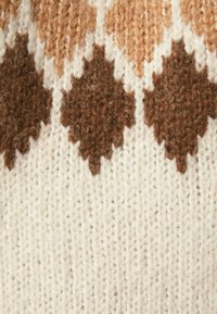 Pull en tricot à base crème présentant un motif de losanges alternés marron et beige, créant un aspect texturé.