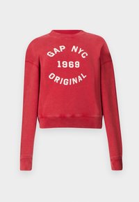 Sudadera corta roja, mezcla de algodón suave, presenta "GAP NYC 1969 ORIGINAL" en letras blancas centralizadas en la parte delantera. Cuello redondo clásico.