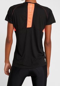 Svart sportt-shirt med strukturerad väv, orange accentpanel på baksidan och kontrasterande sömmar. Kortärmad och med en avslappnad passform.