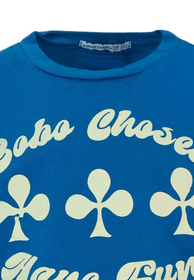 Modrá bavlnená tričko s bielymi symbolmi klubu a textom "Bobo Choses". Okrúhly výstrih a mäkká textúra, ideálne na bežné nosenie.