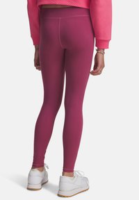 Tajta leggings i en solid djup rosa färg med en slät struktur. Hög midje-design, parat med vita träningsskor.