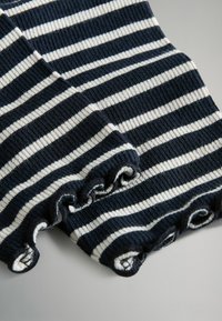 Tessuto a maglia rigato navy e crema con una texture a coste, caratterizzato da bordi a scallop alle maniche per un tocco di dettaglio in più.