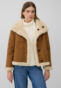 Bruine jas van neppersuède met een pluche, crèmekleurige imitatiebontkraag en boorden, voorzien van zwarte knopen en een cropped ontwerp.