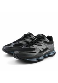 Zapatillas deportivas en negro y gris con parte superior de malla, puntera redonda, diseño curvado y amortiguación visible en la suela para soporte y comodidad.
