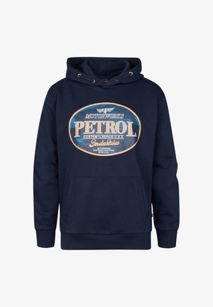 Marineblauer Kapuzenpullover mit "PETROL"-Print auf der Vorderseite, kombiniert mit hellblauen Jeans und weißen Turnschuhen. Der Stoff wirkt weich und lässig.