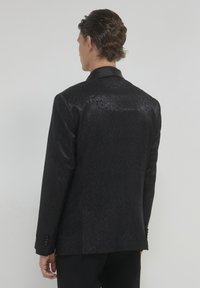 Blazer nero con motivo a stampa, caratterizzato da una texture sottile, rever in satin e chiusura con un bottone, con tre bottoni decorativi sulle maniche.