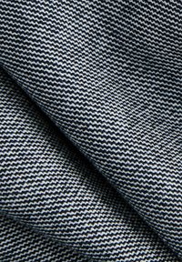 Gros plan sur un tissu serré à motif en zigzag noir et blanc, montrant des plis et des détails de texture.