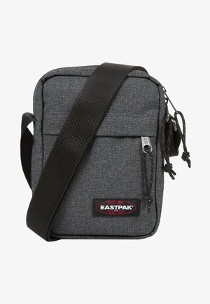 Grå stof crossover taske med en frontlomme, sort rem, lynlås lukning og Eastpak logo patch. Kompakt rektangulært design.