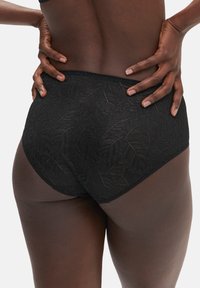 Schwarze Spitzen-Hochschnitt-Unterwäsche mit einem Blattmuster, elastischem Bündchen und glatten Kanten, auf dem Rücken eines Modells positioniert.