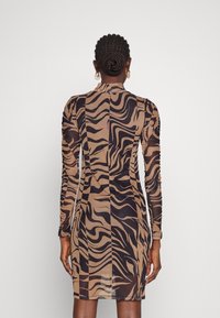 Robe ajustée à manches longues, avec un motif zèbre marron et noir, présentant un tissu texturé et un col haut agrémenté de fronces le long des manches.