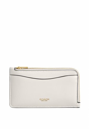 Portefeuille Coach en cuir blanc avec fermeture éclair dorée sur tout le pourtour, fente pour carte à l'avant et logo estampé en doré au centre en bas.