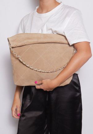 Borsa a tracolla in suede beige con un design a righe, parte superiore pieghevole e una tracolla in metallo argentato. La texture è morbida e liscia, con cuciture diagonali.