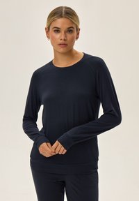 Długi rękaw granatowa bluzka z miękkiego materiału, z okrągłym dekoltem i rękawami raglanowymi, z dopasowanymi mankietami i luźnym krojem.