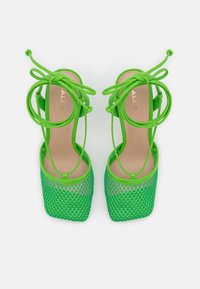 Gröna nät-högklackade sandaler med fyrkantig tår, tunna justerbara remmar och en slät sula. Logotyp präglad på insulan.
