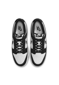 Čierno-biele Nike tenisky s textúrovaným koženým a semišovým zvrškom, obsahujúce kruhové perforácie na špičke a čierne šnúrky.
