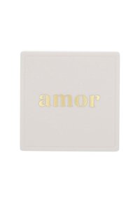 Kwadratowy, jasnoróżowy ceramiczny podkładka z fakturowaną powierzchnią i złotymi literami liternictwa "amor". Minimalistyczny, nowoczesny design.