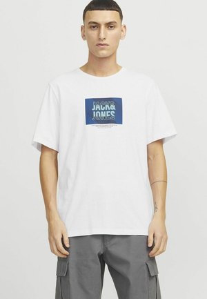 Bijela pamučna majica s plavim grafičkim kvadratom na kojem piše "JACK&JONES". Opusten kroj s kratkim rukavima, glatka tekstura i okrugli izrez.