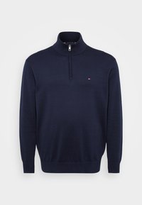 Granatowy sweter z dzianiny z zamkiem błyskawicznym do jednej czwartej długości, żebrowanym kołnierzem i mankietami, z małym logo po lewej stronie klatki piersiowej. Gładka tekstura.