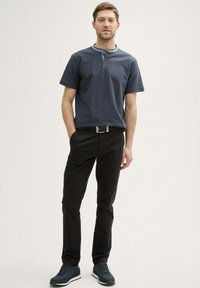 Polo a maniche corte blu navale con un motivo testurizzato e una chiusura a due bottoni, abbinato a pantaloni neri e sneakers blu navale.