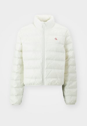Chaqueta acolchada blanca recortada con un alto cuello, presenta un cierre frontal y el logo rojo de CK en el lado izquierdo del pecho. Material suave y brillante.