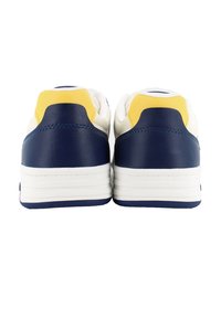 Sneakers con corpo bianco, tallone e dettagli blu navy, e una linguetta gialla sul retro. Texture in pelle liscia, suola imbottita.