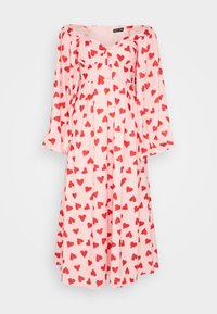 Långärmad midi-klänning i rosa med mönster av röda hjärtan, avskuren axelkrage, figurnära byst med knappar och en flödande kjol.