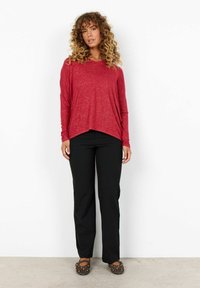 Rode lange mouwen, losvallend shirt met een ronde halslijn en een asymmetrische zoom, gecombineerd met zwarte rechte broek en bruine schoenen.