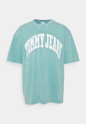 T-shirt à manches courtes bleu sarcelle clair avec l'inscription « TOMMY JEANS » en grandes lettres blanches courbes sur le devant.
